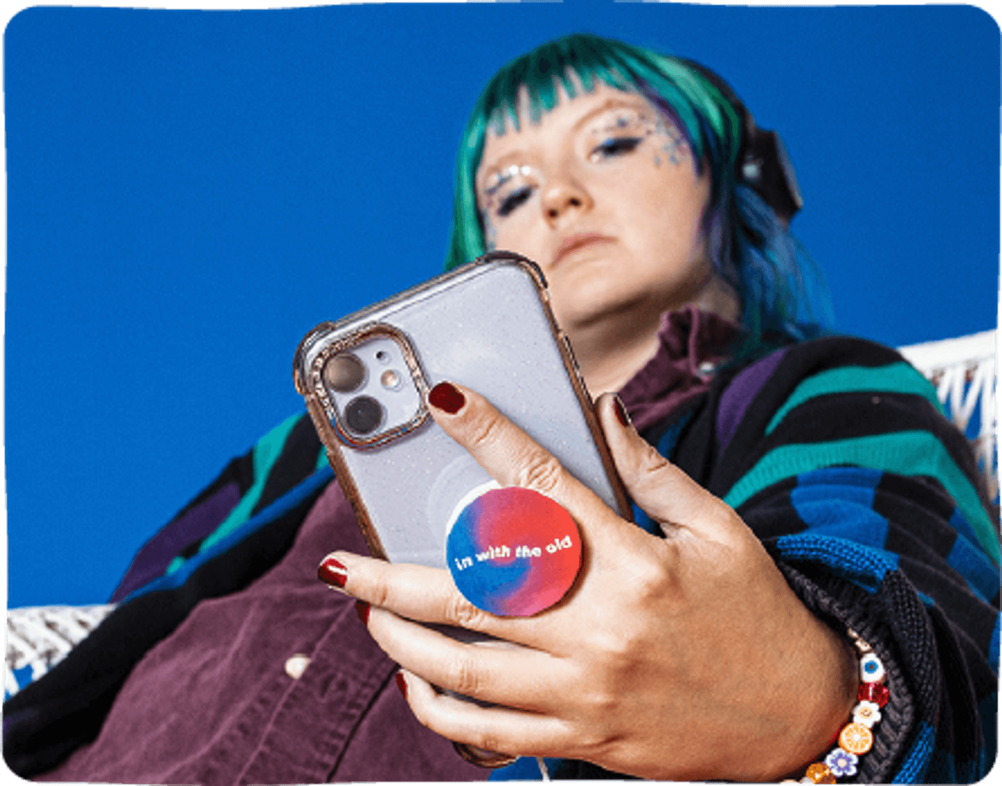 Someone looking down at their phone which features a Time After Time themed pop socket. The pop socket reads "in with the old".