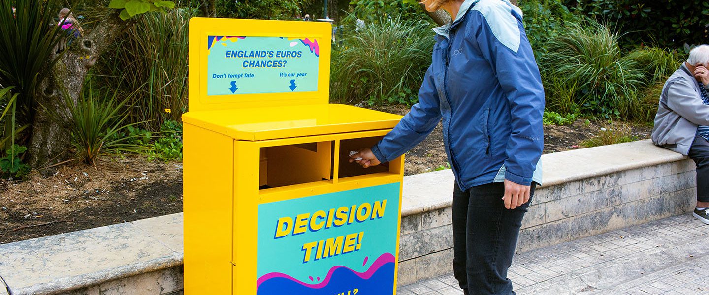 Someone dropping their rubbish into a colourful ballot bin.