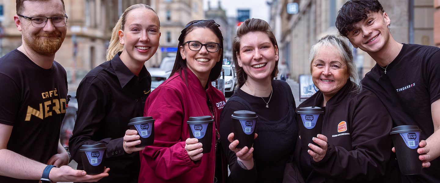 A line of employees from each of the participating Borrow Cup brands each holding a Borrow Cup and smiling