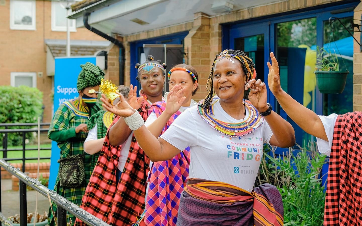 A group of people dressed in traditional African clothing celebrating the launch of a community fridge in Manchester.