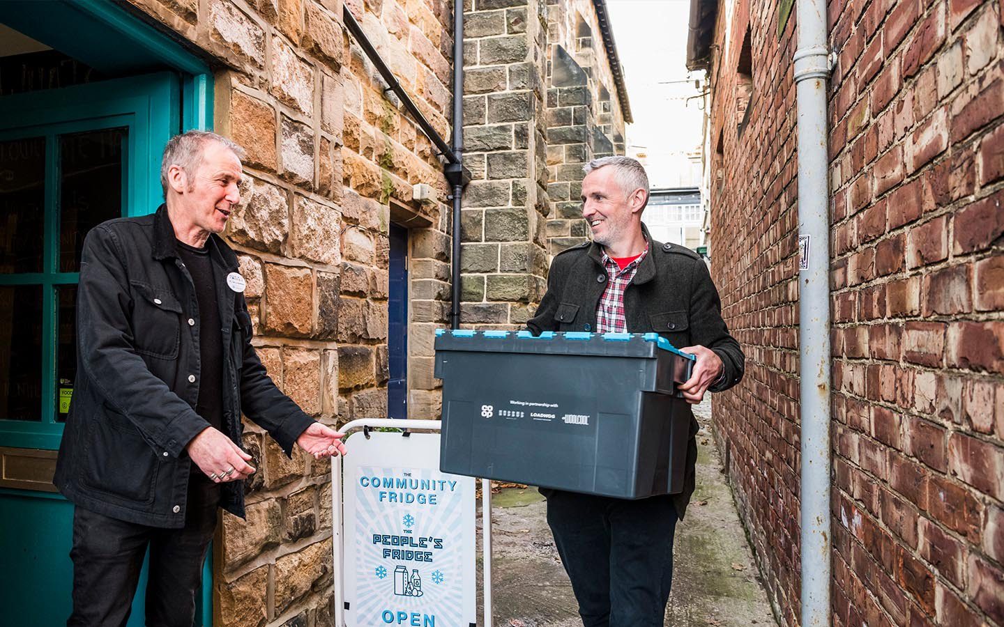 Community fridge volunteers dropping off a food donation.
