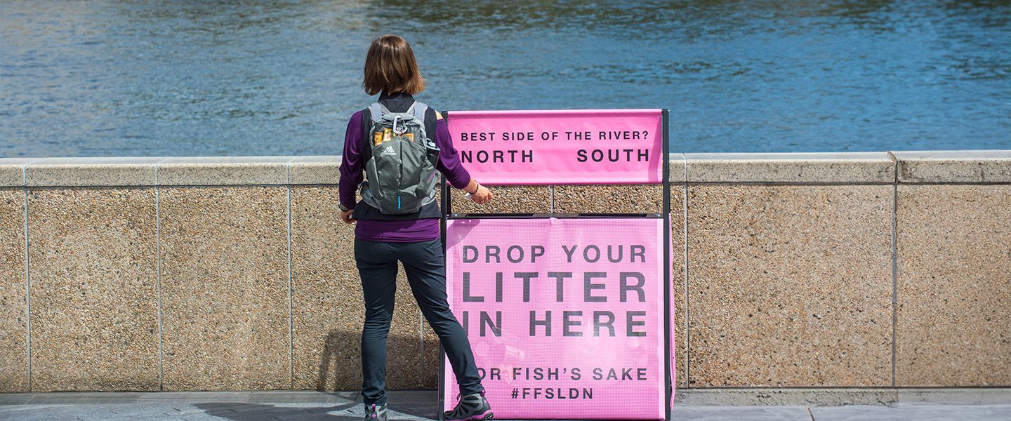 Someone standing next to a bin overlooking a river.