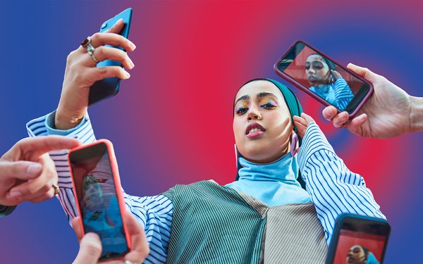 A young woman with a headscarf and colourful eyeshadow is holding a phone to take a selfie. Around her are lots of different people holding phones taking her picture. The background is a graphic image of a purple and blue swirl.