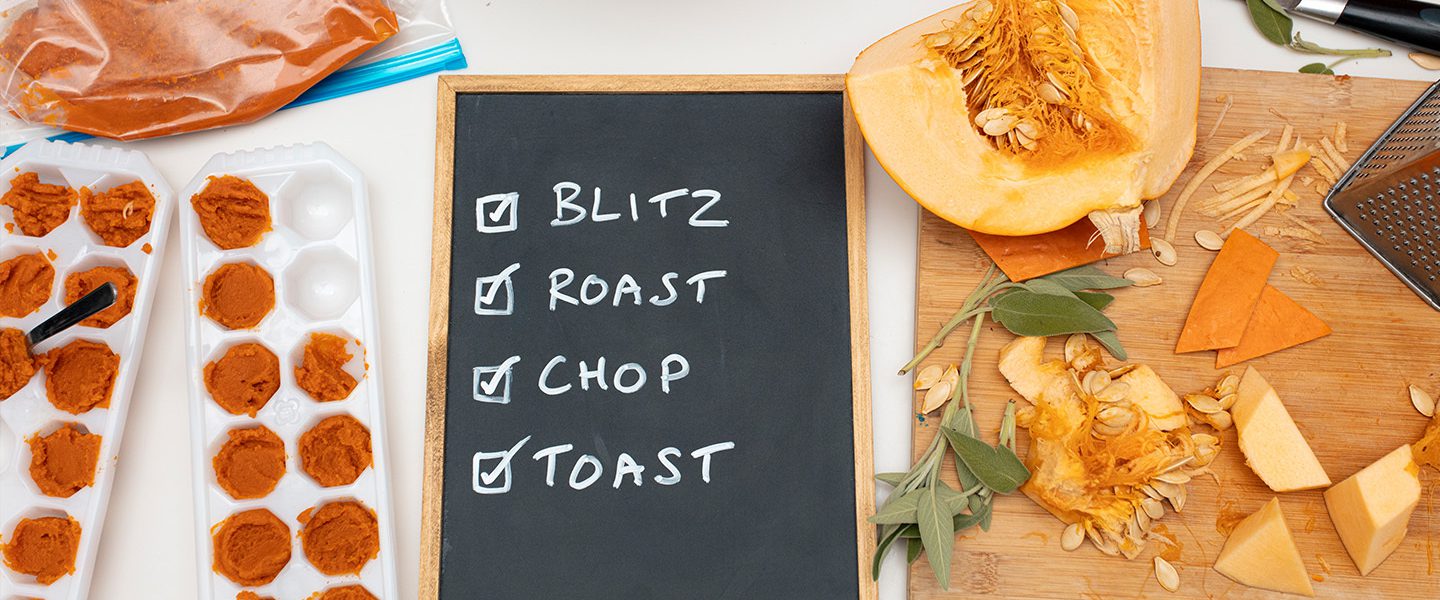 Pumpkin being cooked in various way on a kitchen counter ready to be made into Halloween pumpkin recipes. The pumpkin is shown pureed in cupcake moulds and chopped on a chopping board. In the middle, a blackboard lists 'blitz, roast, chop, toast' with checkmarks in front of each word.