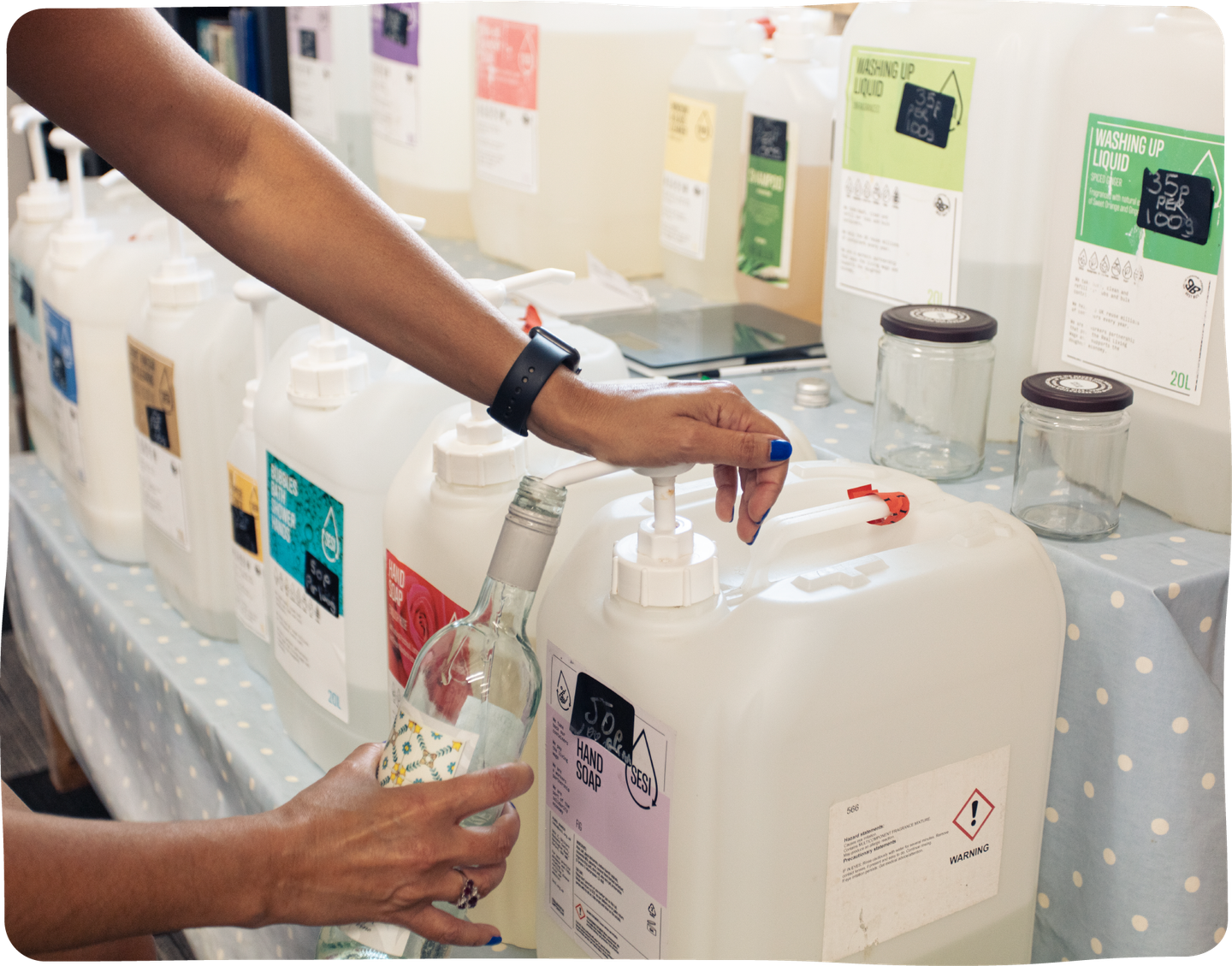 Someone fills an empty wine bottle with soap at a refill station.