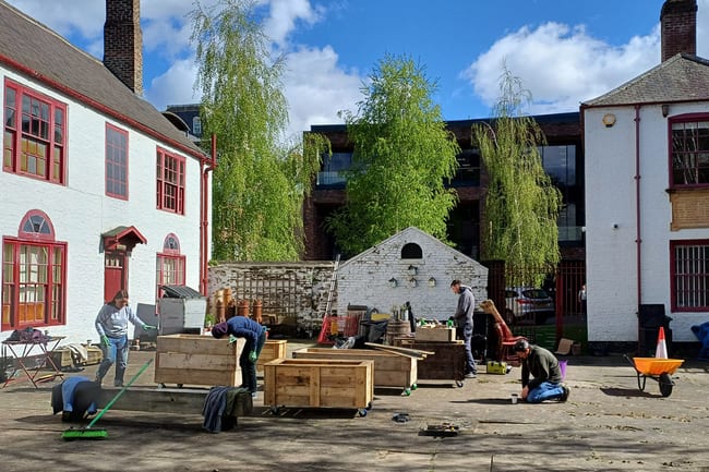 A group of people outdoors, building planter beds in the courtyard behind the theatre