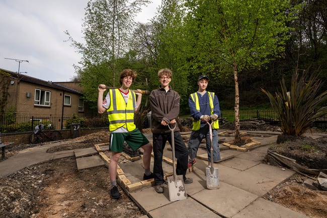 Three young gardeners standing in the middle of an upturned garden work in progress