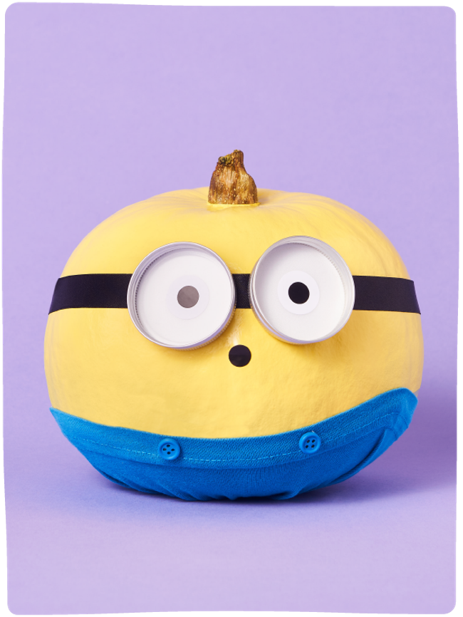 Pumpkin painted and decorated like a Minion from Despicable Me sat against a light purple backdrop.